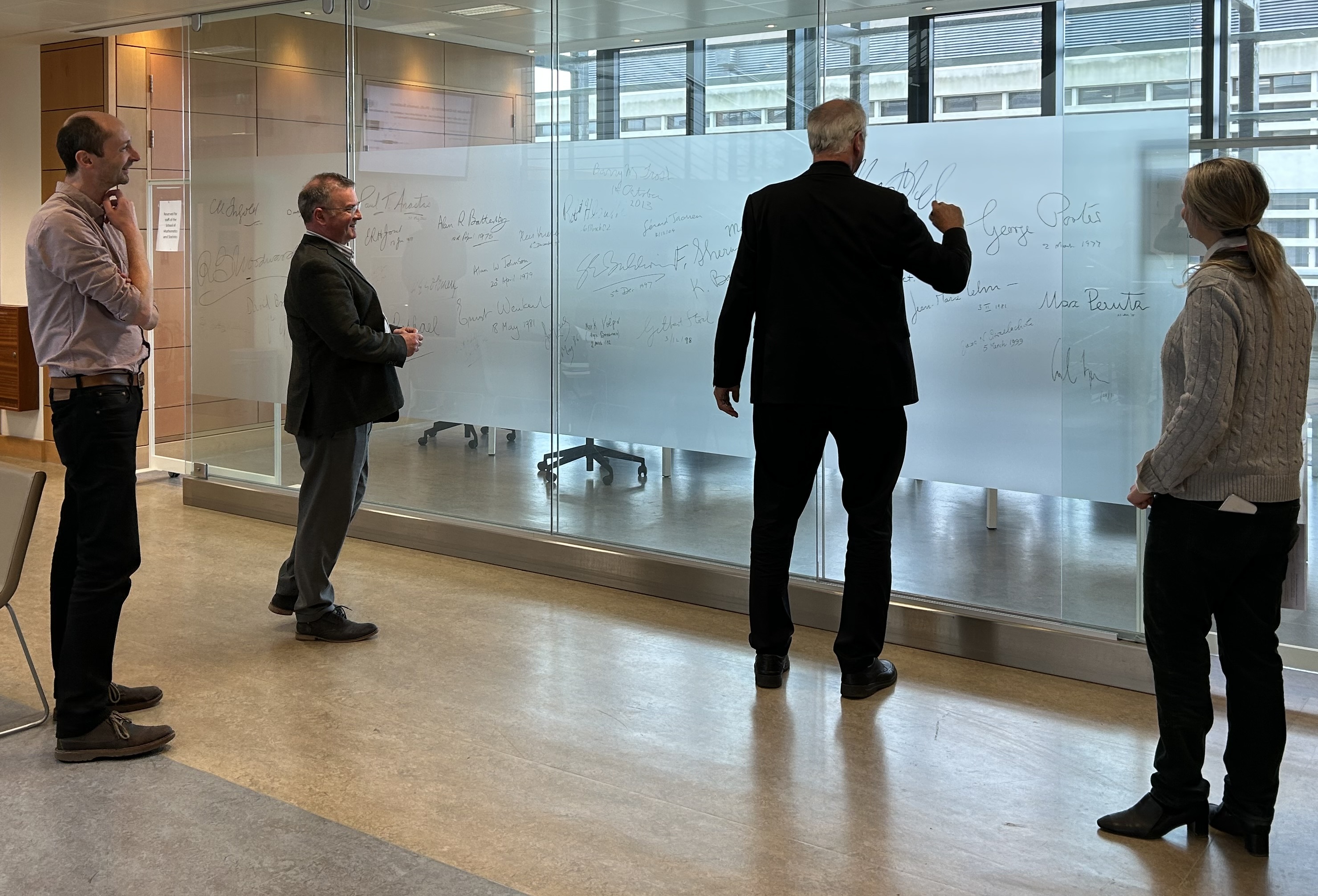 man signing a glass wall